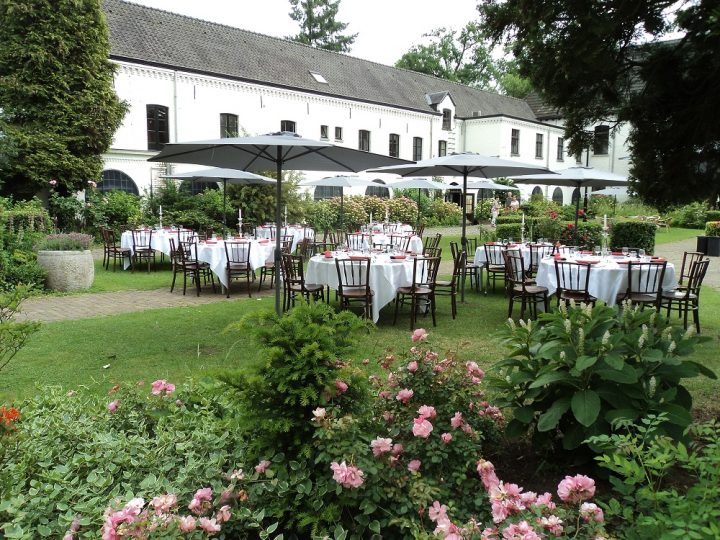 Gedekte tafels en parasols in de groene binnentuin van De Berckt