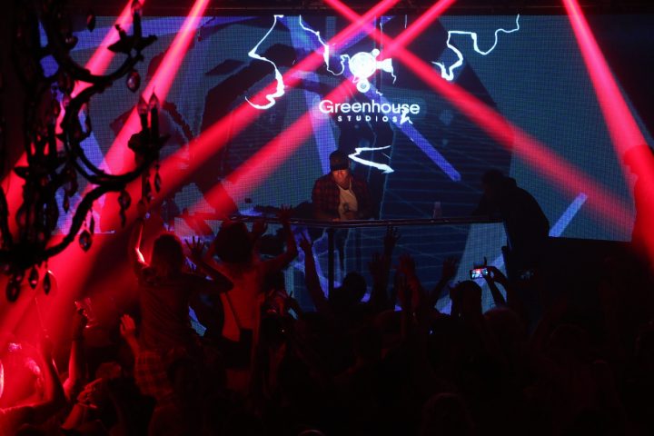 DJ en feestende gasten onder rode lichtstralen in de kapel